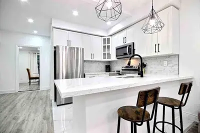 a kitchen with white cabinets and two bar stools at Modern Luxury Home next to Tim Hortons Field in Hamilton