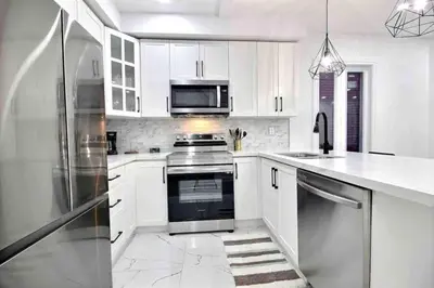 a white kitchen with a stove and a refrigerator at Modern Luxury Home next to Tim Hortons Field in Hamilton