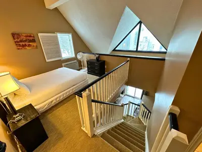 a room with a bed and a staircase with a window at Mountain Loft Suite with Pool and Hot Tub in Blue Mountains