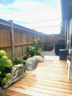 a wooden deck with rocks and a fence at The 1883 Century Flat Suite in Collingwood