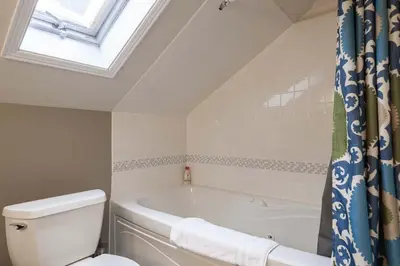 a bathroom with a bath tub and a toilet at Stone Maiden Inn in Stratford