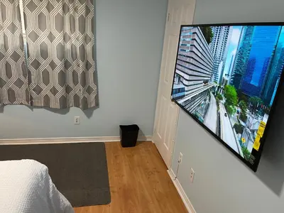 a bedroom with a large flat screen tv on a wall at Comfort Quest in Oshawa