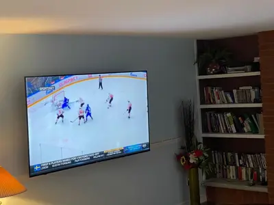 a flat screen tv hanging on a wall with a hockey game at Comfort Quest in Oshawa