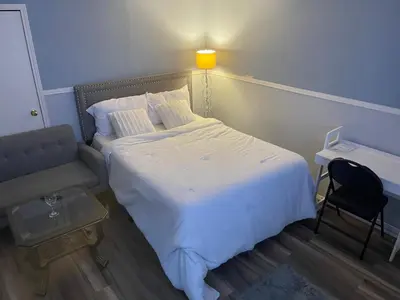 a bedroom with a bed and a chair and a lamp at Comfort Quest in Oshawa