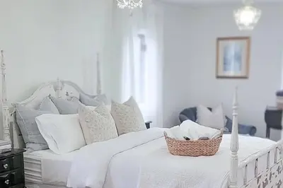 a white bed with white pillows and a basket on it at Vintage Farmhouse with Hot Tub on Vineyard in Waterford