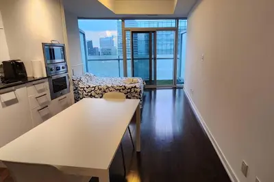 a living room with a white table and a kitchen at Modern studio High Floor ,CN Tower, ScotiaArena in Toronto