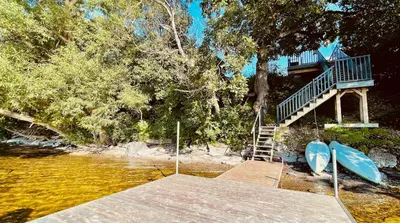 a house with a deck and two surfboards on a dock at Lakeside Maison in Hillier