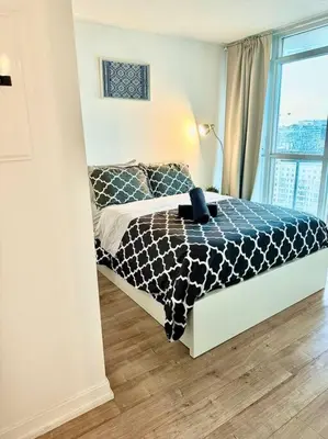a bedroom with a black and white bed with a window at Stylish Condo Downtown Near CN Tower - Free parking in Toronto