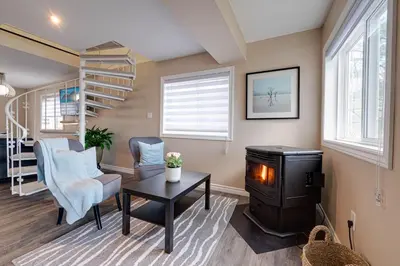 a living room with a wood stove and a staircase at Muskoka Waterfront Cottage - Moon River with HOT TUB in Bala