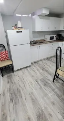 a kitchen with white cabinets and a wooden floor at Elegant & Luxurious 3 Bedroom Home in Mississauga