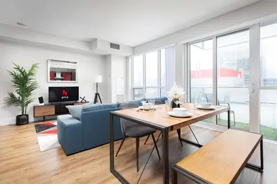 a living room with a blue couch and a table at Perfect Condo Sleeps 4 Across from Cn Tower! in Toronto