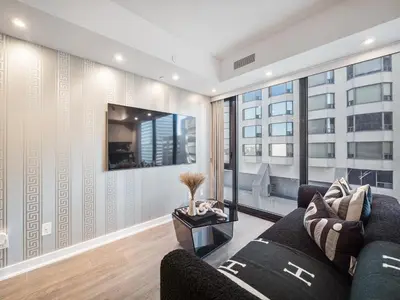 a living room with a couch and a large window at Hazelton Suites - Yorkville - Indoor Pool & Hot Tub in Toronto