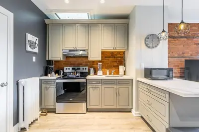 a kitchen with white cabinets and a clock on the wall at 1BR - Queen Bed Apartment in Hamilton's Best Neighborhood in Hamilton