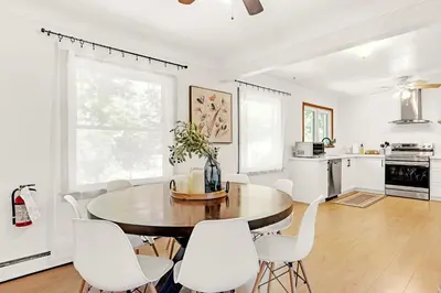 a kitchen and dining room with a wooden table and white chairs at Walk to Lake - Old Town Retreat in Niagara on the Lake