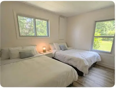 two beds in a room with two windows at Cottage on Private Beach in Penetanguishene