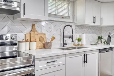 a white kitchen with white cabinets and a sink at Modern 3 Bdr Homeapt Mins To Notlwineriesfalls in St. Catharines