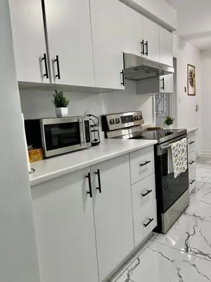 a white kitchen with white cabinets and a microwave at Private Room Near Airport K3 in Mississauga