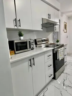 a white kitchen with white cabinets and a microwave at Private Room Near Airport K2 in Mississauga