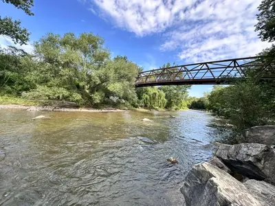 a bridge over a river with rocks and trees at Riverwood Home-Entire Rental Unit in Mississauga