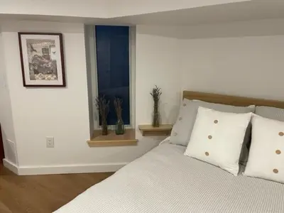 a bedroom with a bed with pillows and a window at Lower level newly renovated studio apartment in central downtown location in Toronto