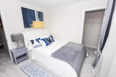 a white bedroom with a bed with blue pillows at JNShortStay- Niagara Falls Area Hidden Gem in Welland
