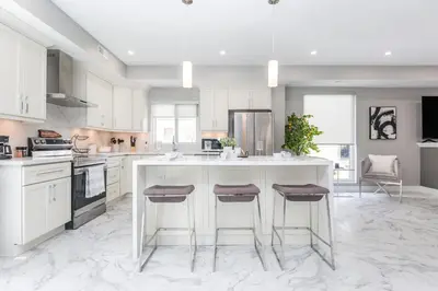 a kitchen with white cabinets and a island with bar stools at Lake House By Lis in Innisfil