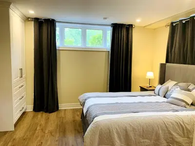 a bedroom with a large bed and a window at Cozy 1 bedroom basement apartment 14 days minimum in Fonthill