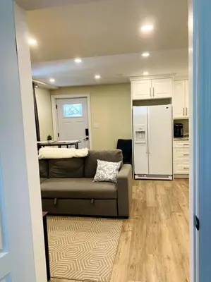 a living room with a couch and a kitchen at Cozy 1 bedroom basement apartment 14 days minimum in Fonthill