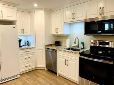 a kitchen with white cabinets and a black appliance at Cozy 1 bedroom basement apartment 14 days minimum in Fonthill