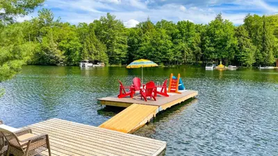 a dock with chairs and an umbrella on a lake at Summit Cottage on Kawagama Lake in Dorset