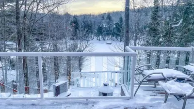 a snow covered balcony with a table and a chair at Summit Cottage on Kawagama Lake in Dorset