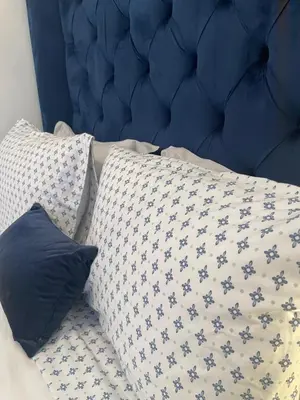a bed with a blue head board and two pillows at Serenity Inn in Niagara Falls