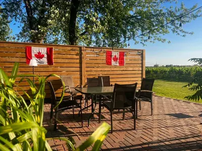 a patio with a table and chairs in front of a fence at Sunset Suites in Niagara Wine Country in Niagara on the Lake