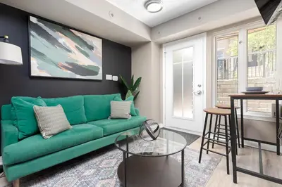 a living room with a green couch and a table at Lakeside Haven - Cozy Townhome in Liberty Village in Toronto
