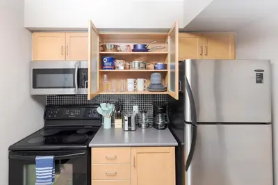 a kitchen with a stainless steel refrigerator and wooden cabinets at Lakeside Haven - Cozy Townhome in Liberty Village in Toronto