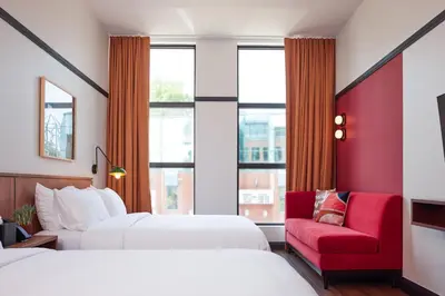 a hotel room with two beds and a red chair at The Postmark Hotel in Newmarket