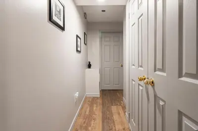 a hallway with a white door and a wooden floor at Modern, basement apartment, close to airport in Toronto