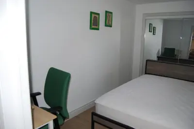 a bedroom with a bed and a desk and a green chair at Modern 2-BR Basement Apartment in Richmond Hill
