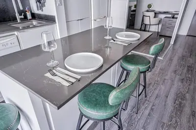 a kitchen with green chairs and a counter with wine glasses at Designer 2BR Downtown Condo, Rogers Center in Toronto