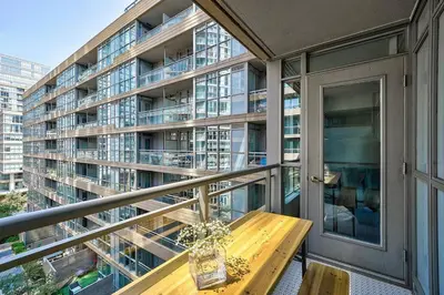 a balcony with a wooden table and a large building at Designer 2BR Downtown Condo, Rogers Center in Toronto