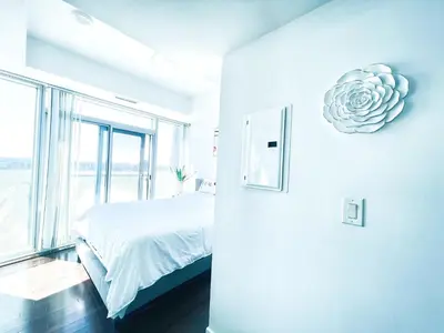 a white bedroom with a bed and a large window at Superior Lakeview Luxury 3-Bedroom Suite on High Floor in Toronto