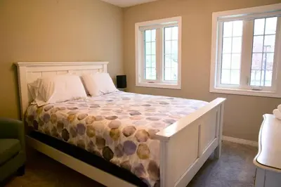 a bedroom with a large bed with two windows at Cozy, 4 Bedroom Chalet, 10 min walk to Village in Blue Mountains
