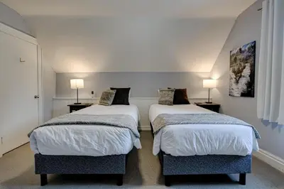 two beds in a small room with two lamps at Historic Home in the Heart of Elora in Elora