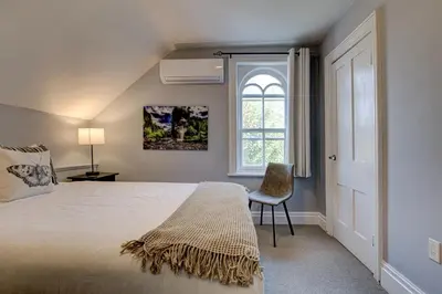 a bedroom with a bed and a window and a chair at Historic Home in the Heart of Elora in Elora
