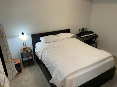 a bedroom with a bed with white sheets and a lamp at Modern, well-equipped, and centrally located in Fonthill