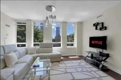 a living room with a white couch and a tv at 1560 sqft Elegant Condo at Downtown Hi-End Shopping & Dining Area - CN Tower View, Bidet, LockBox in Toronto