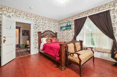 a bedroom with a bed and a chair in it at Marmora and Lake Inn and Victorian Diner - Grand Victorian Suites- Level 2 in Marmora