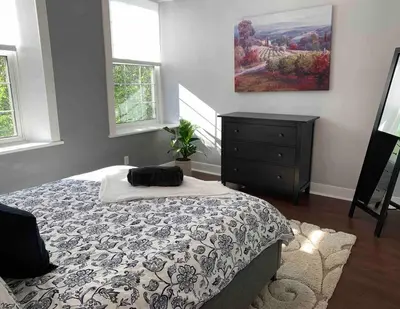 a bedroom with a bed and a dresser and windows at Stone Mill Retreat - Rustic Cozy Getaway with Loft! in Fergus