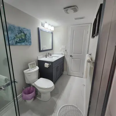 a bathroom with a toilet and a sink and a mirror at Cozy Hideaway in Thorold