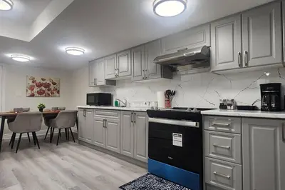 a kitchen with white cabinets and a table with chairs at Cozy Hideaway in Thorold